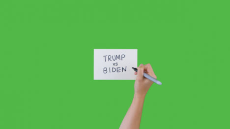 Woman-Writing-Trump-vs-Biden-on-Paper-with-Green-Screen